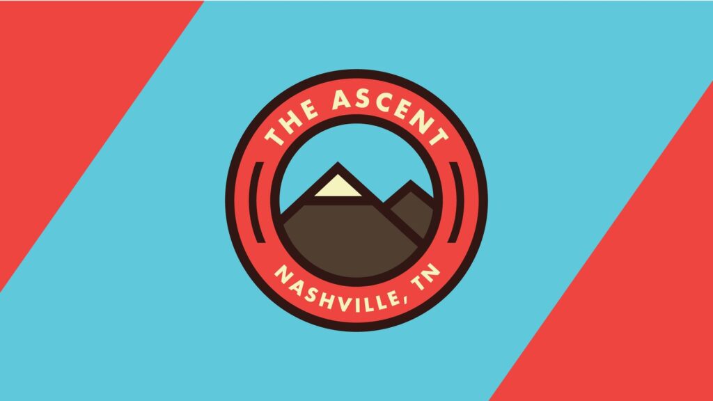 A circular logo with The Ascent Nashville, TN in red around a graphic of two brown mountains and a white peak, set against a blue background with red diagonal corners.