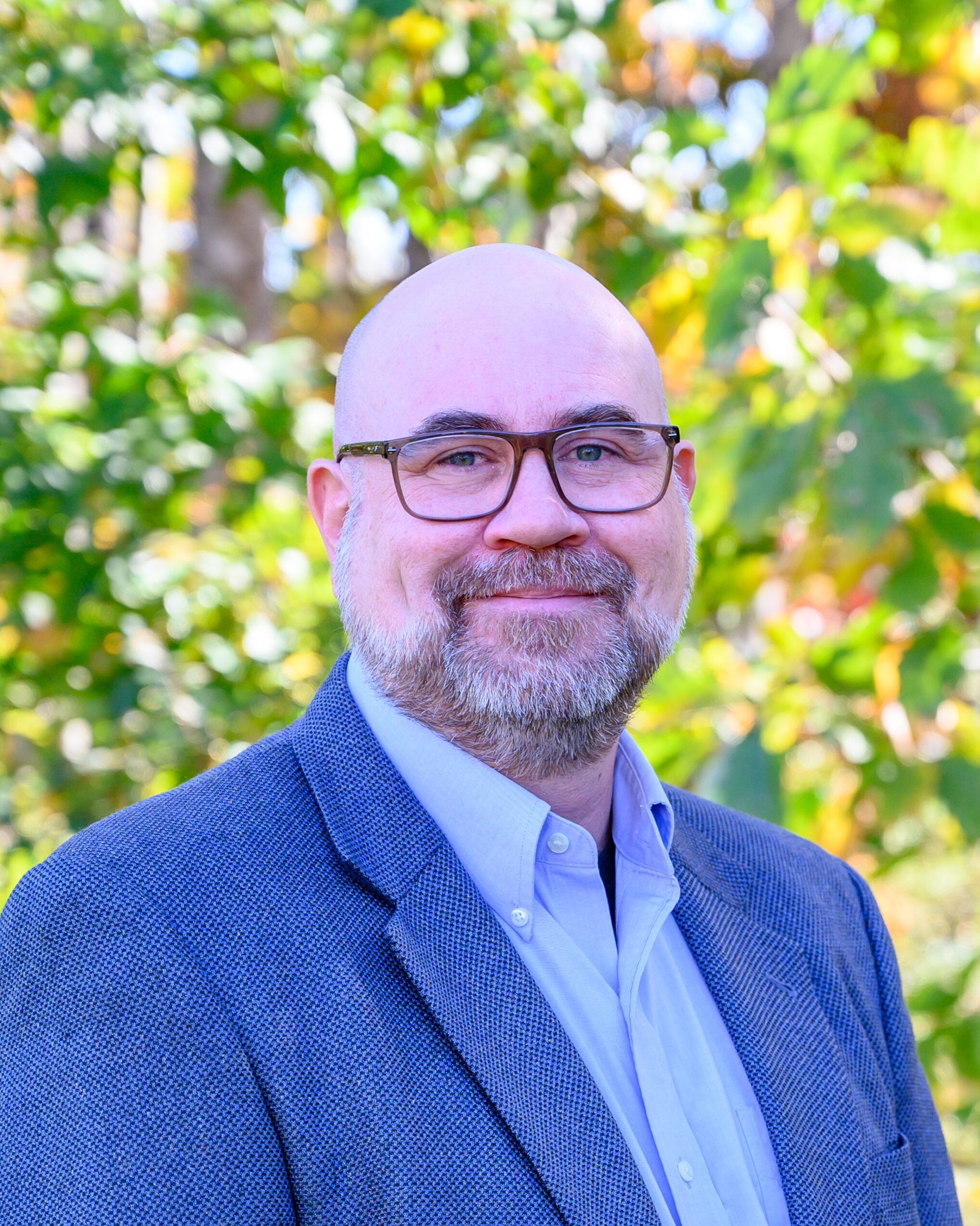 A man wearing glasses and a blue jacket.